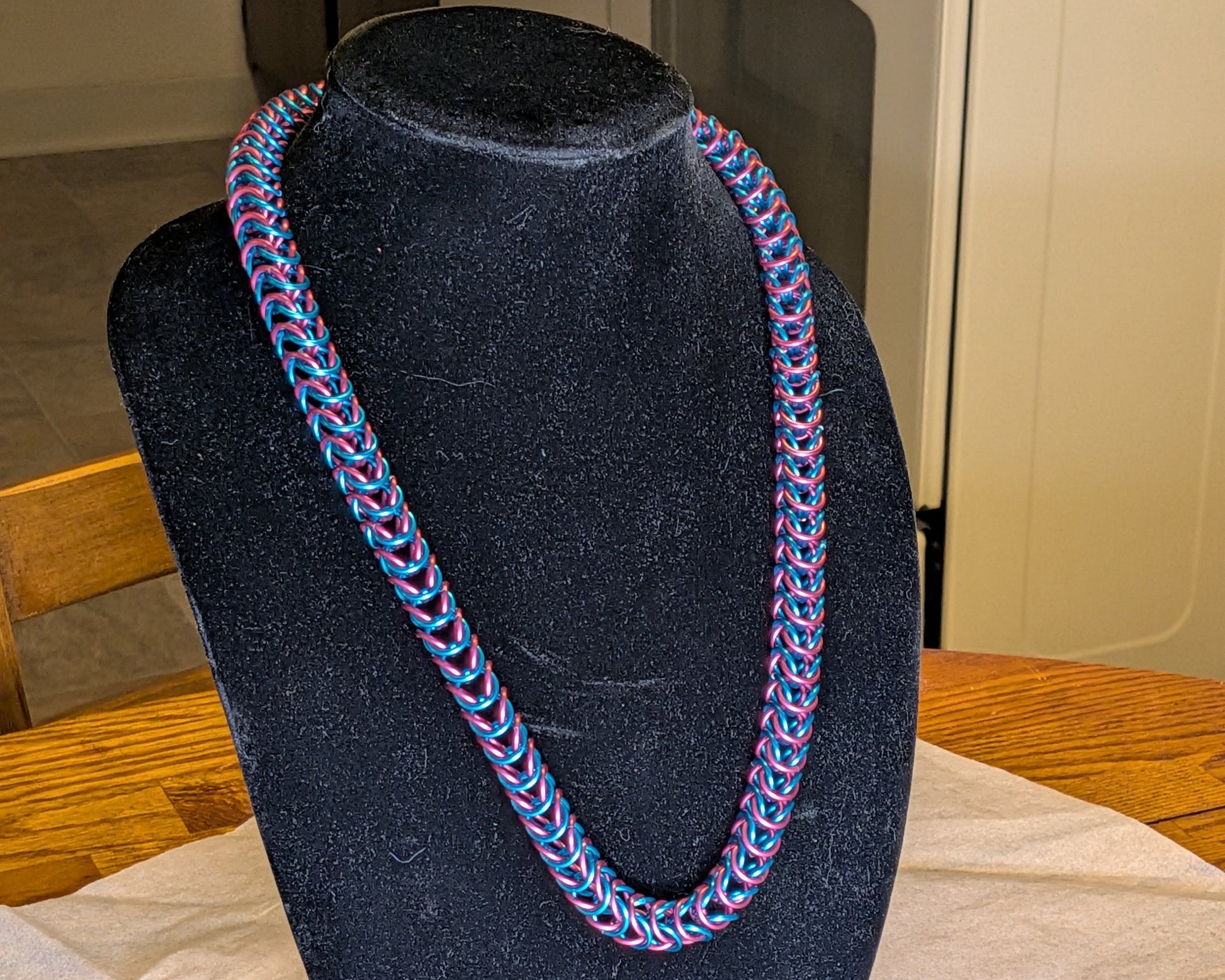 Necklace on a black bust against a neutral background